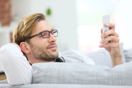 Man relaxing in sofa with smartphone and headphones