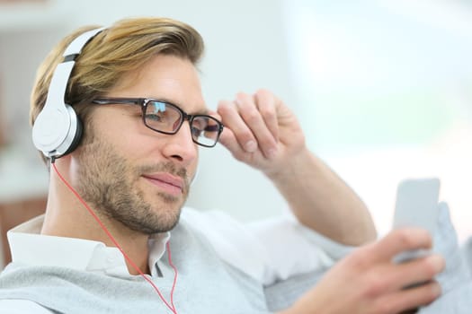 Man relaxing in sofa with smartphone and headphones