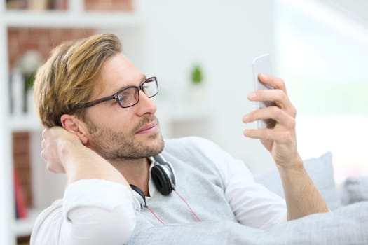 Man relaxing in sofa with smartphone and headphones