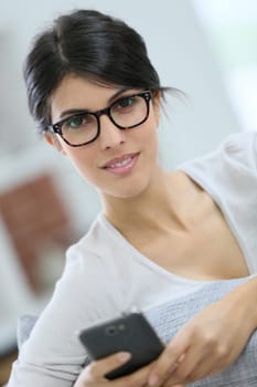 Young woman with eyeglasses reading message on phone