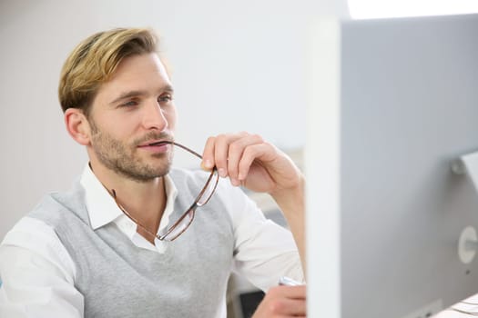 Businessman with eyeglasses sitting in front of desktop computer screen