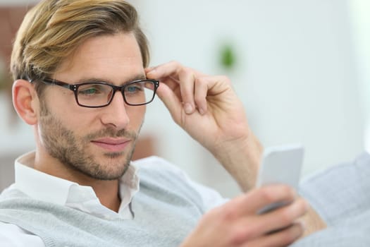 Man with eyeglasses reading message on smartphone