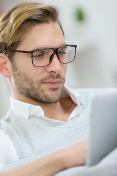 Man with eyeglasses connected on digital tablet at home