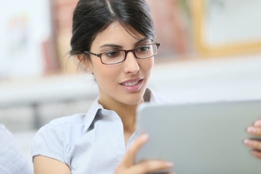Young woman with eyeglasses using digital tablet