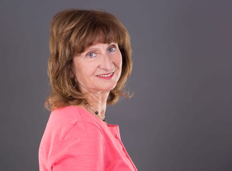 older caucasian woman wearing casual outfit on grey background