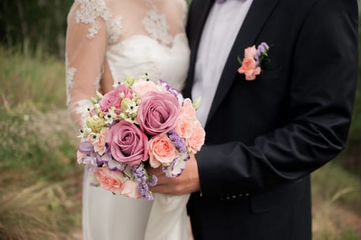 wedding couple hugging, the bride holding a bouquet of flowers in her hand, the groom embracing her