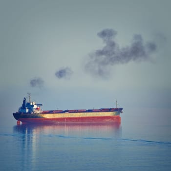 Fuming Bulk Carrier Ship in the Black Sea at the Evening