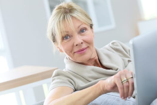 Senior woman with eyeglasses using digital tablet at home