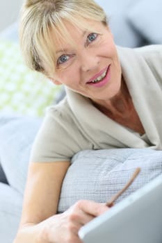 Senior woman with eyeglasses using digital tablet at home