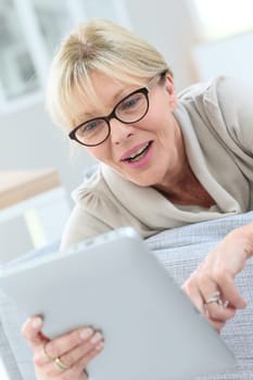 Senior woman with eyeglasses using digital tablet at home