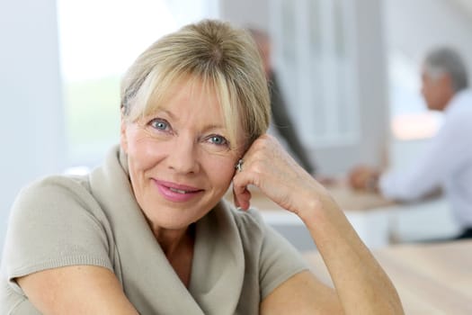 Portrait of smiling senior woman, people in background