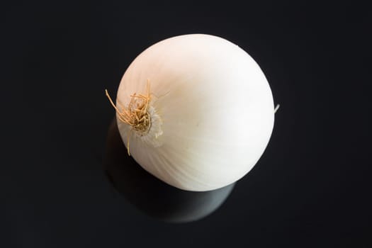 Fresh white onions peeled on a black background with reflection and text space