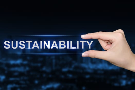 hand pushing sustainability button on blurred blue background