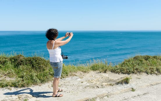a beautiful woman takes a picture of the ocean