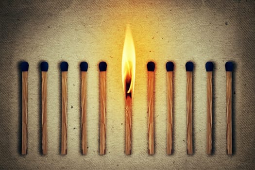 Burning match standing middle a row of whole, new matches