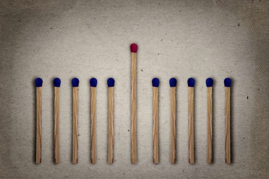 Red match standing middle a row of blue ones. Standing out from the crowd, leadership, difference concept