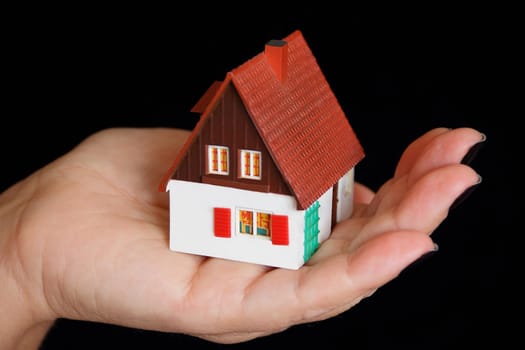Image of dollhouse in human hand on black background