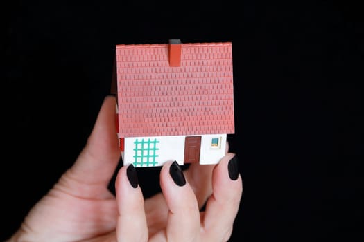 Image of dollhouse in human hand on black background