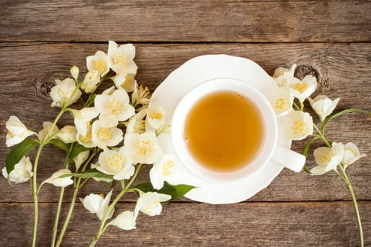 Top view of teacup and blooming flowers on wooden background