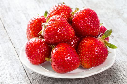 White plate with strawberries on wooden background