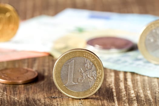 Detail of one euro coin, other euro coins and notes in background