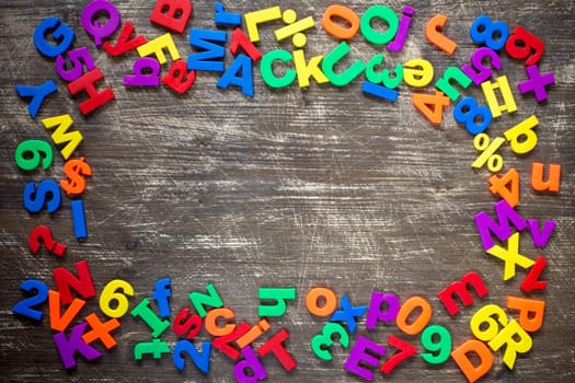 Top border of colorful  magnetic letters and numbers over a wooden background