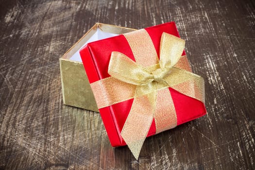 Open gift box with golden ribbon on the old wooden floor