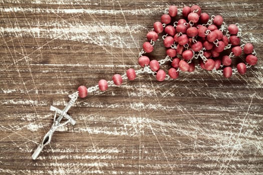 Old wooden scratched background and catholic rosary