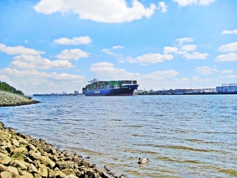 Hamburg, Germany - May 24, 2008: Big containership on the river Elbe, in the backgrount the harbor of Hamburg.