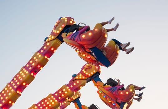 Hanging funfair attraction with people having fun. low angle view