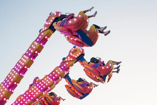 Hanging funfair attraction with people having fun. low angle view