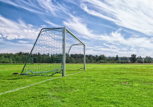 Soccer Goal on Soccer Pitch with a partly cloudy sky and trees.