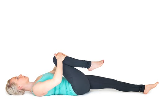 Full body view of a young blonde woman doing yoga exercises against a white background with a slight shadow