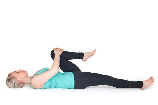 Full body view of a young blonde woman doing yoga exercises against a white background with a slight shadow