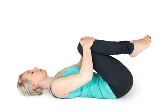 Full body view of a young blonde woman doing yoga exercises against a white background with a slight shadow