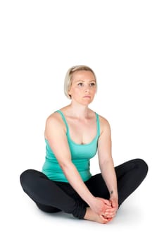 Full body view of a young blonde woman doing yoga exercises against a white background with a slight shadow