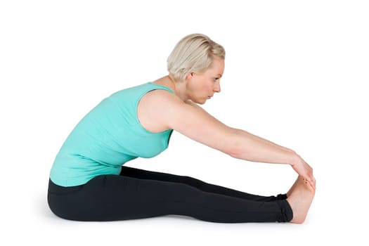 Full body view of a young blonde woman doing yoga exercises against a white background with a slight shadow
