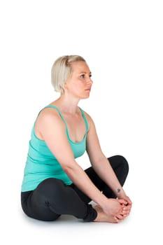 Full body view of a young blonde woman doing yoga exercises against a white background with a slight shadow