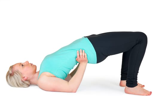 Full body view of a young blonde woman doing yoga exercises against a white background with a slight shadow
