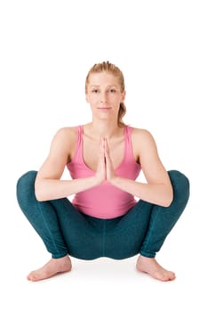 Full body view of a young blonde woman doing yoga exercises against a white background with a slight shadow