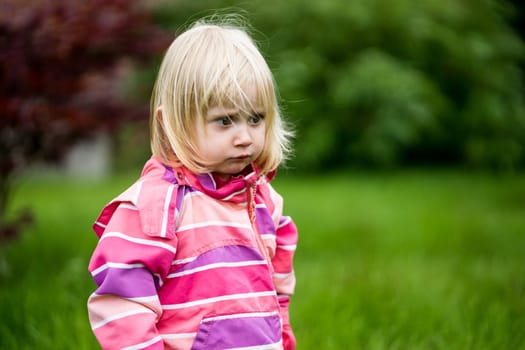 Sad or bewildered girl standing alone in the garden