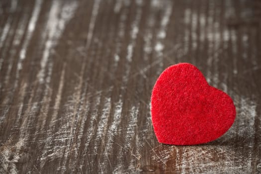 Old scratched wooden background with a small red heart