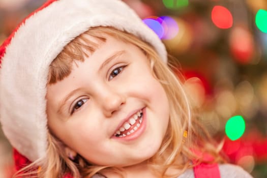 Cute Christmas girl with the Christmas tree lights bokeh in the background