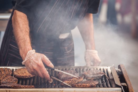 Chef  preparing burgers at the barbecue outdoors