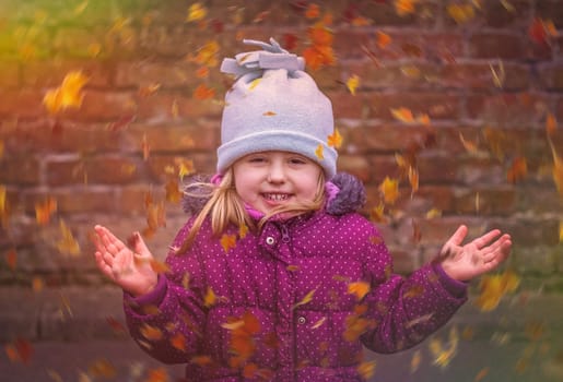 Portrait of a cute girl with swirling leaves in autumn