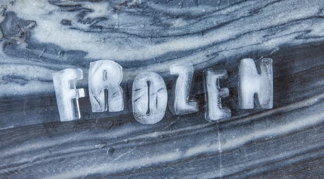 Frozen lettering made of ice rock on dark marble