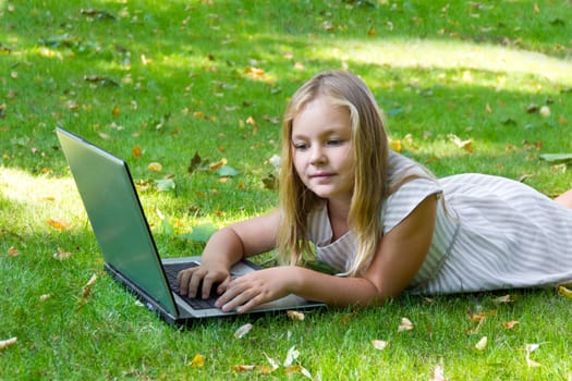 Image of cute girl with laptop on green grass