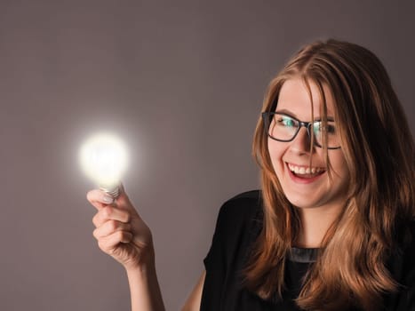 Cheerful female student with a glowing light bulb, great idea concept