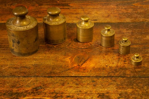 Different vintage brass weights unit on wood floor background