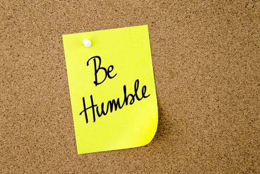 Be Humble written on yellow paper note pinned on cork board with white thumbtacks, copy space available